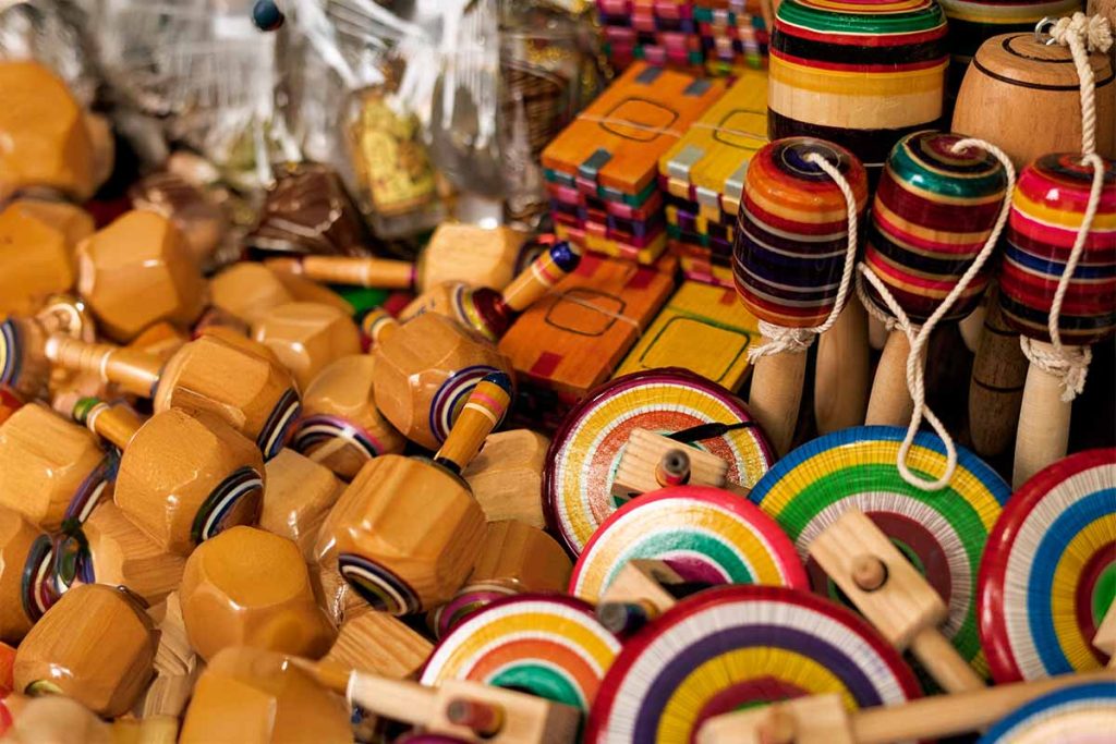 Conjunto de juguetes mexicanos de madera, son de distintas formas, decorados con detalles con pintura de colores vibrantes y variados.