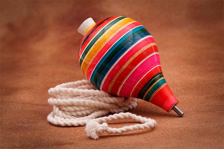 Trompo mexicano echo de madera y adornado con pintura de distintos colores vibrantes.
