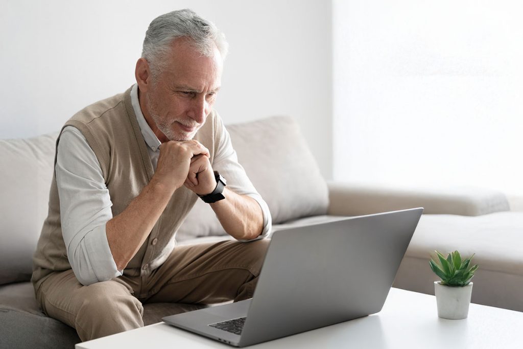 Persona de edad avanzada consultando un plan funerario en su laptop.